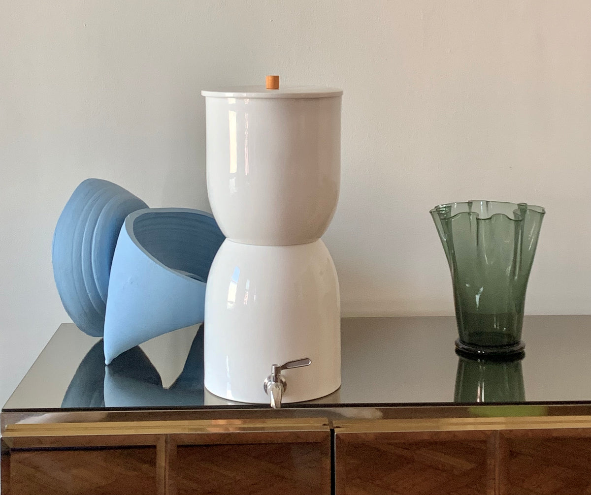 a White Walter sits on a sideboard surrounded by decorative vases